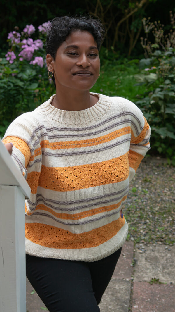 Sweater med vandrette striber. Den er free-sized (one size fits all) og strikket i farverne grå, creme og orange.