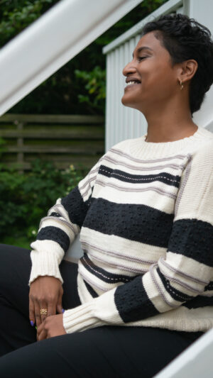 sweater med vandrette striber. Den er free-sized (one size fits all) og strikket i farverne grå, creme og sort.